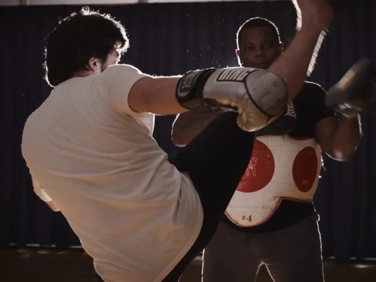 Instructor MJ holding a body shield as a student throws a high kick